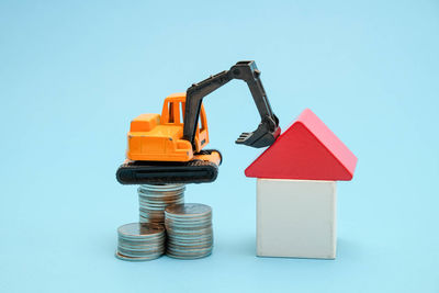 Close-up of toy with coins and model home against blue background