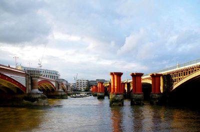 Bridge over river against cloudy sky