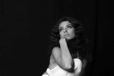 Portrait of beautiful young woman against black background