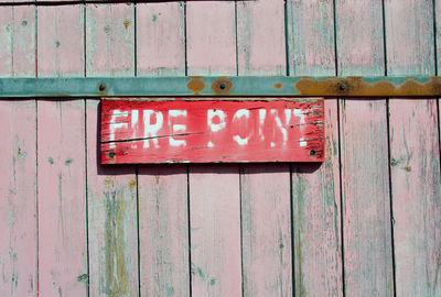 Close-up of text on red placard over wooden wall