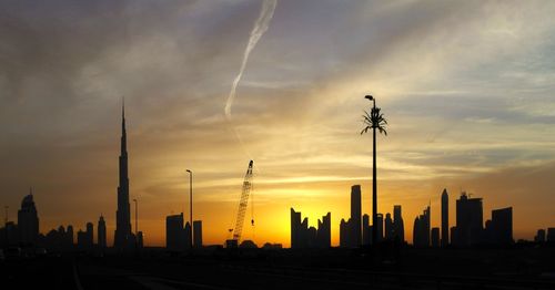 Silhouette burj khalifa against sky during sunset in city