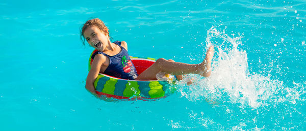 Portrait of smiling girl splashing in swimming pool