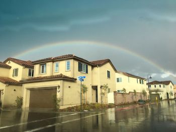 Rainbow over buildings in city against sky