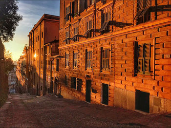 Street amidst buildings against sky at sunset