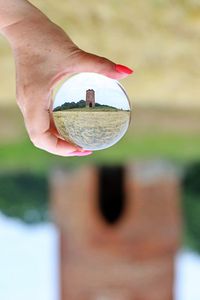 Close-up of hand holding crystal ball outdoors