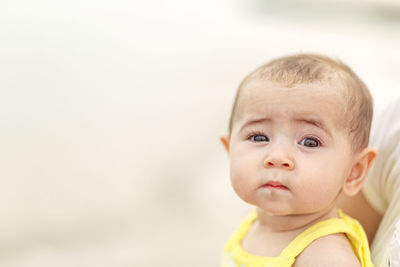 Infant baby with bright eyes isolated with shallow depth of field against light colored background
