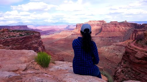 Rear view of woman sitting against canyons in utah