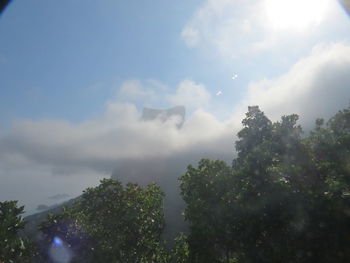 Low angle view of sunlight streaming through clouds