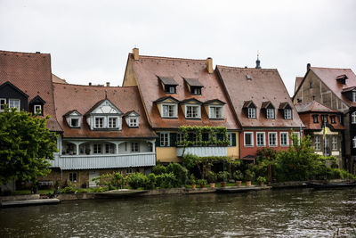 Houses by river and buildings against sky