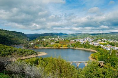 Scenic view of river and mountains against cloudy sky