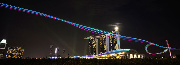 Panoramic view of light trails against illuminated marina sands bay