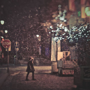 Woman walking in illuminated city at night