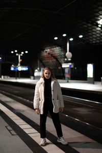 Portrait of young woman standing in city during winter at night