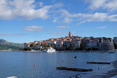 Aerial view of townscape by sea against sky