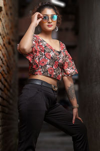 Portrait of beautiful young woman standing against wall