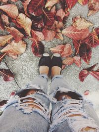 Low section of woman standing on autumn leaves