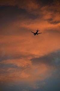 Low angle view of silhouette airplane against sky during sunset