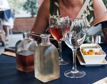 Close-up of wine bottles and glasses served for woman on table