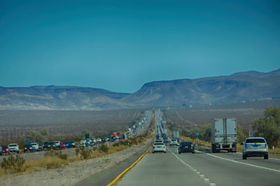 Road leading towards mountains against blue sky