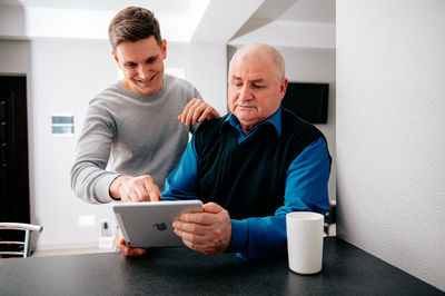 Man teaching tablet pc to grandfather at home