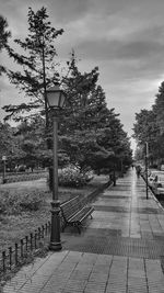 Street light on footpath in city against sky