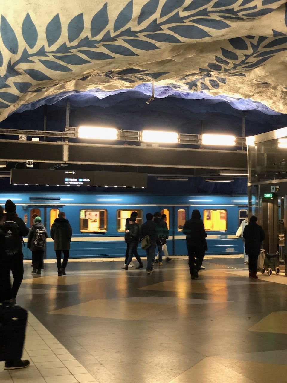 GROUP OF PEOPLE WALKING IN ILLUMINATED UNDERGROUND STATION