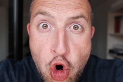 Close-up portrait of shocked man at home