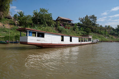 House by lake against sky