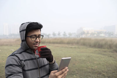 Young man using mobile phone on field