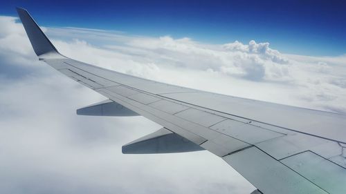 Airplane wing over clouds against sky