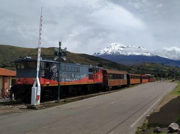 Train on railroad track by mountain against sky