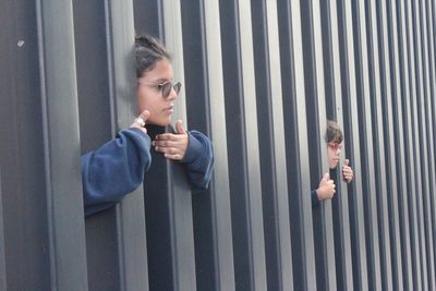 Siblings looking through metallic fence
