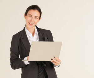Portrait of smiling young man using smart phone against white background
