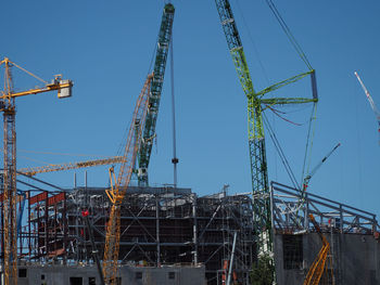 Cranes by incomplete buildings at construction site