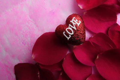 Close-up of love text on heart shape with rose petals