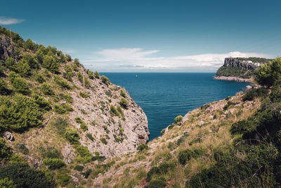 Scenic view of sea by mountains against sky