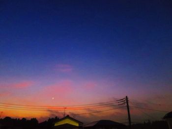 Low angle view of silhouette electricity pylons against sky during sunset