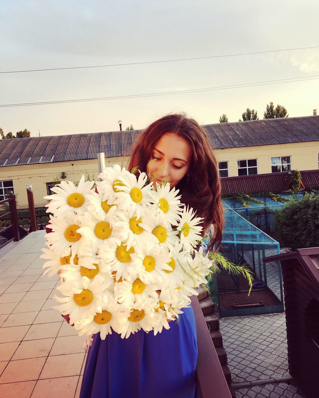 flower, built structure, lifestyles, freshness, fragility, casual clothing, leisure activity, portrait, day, outdoors, petal, flower head, plant, sky, focus on foreground, blooming, nature, growth, in bloom