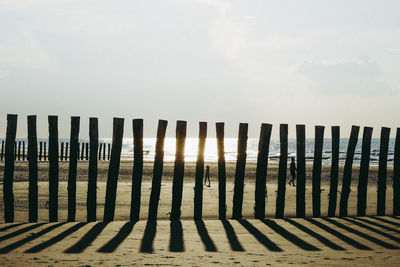 Shadow of wooden fence on land against sky