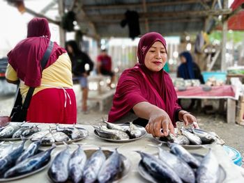 Portrait of smiling woman holding fish in market