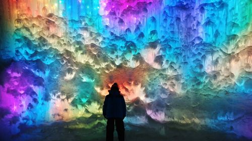 Rear view of silhouette man standing against multi colored light
