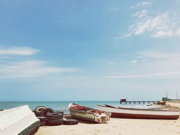 Fishing boats moored at beach against sky