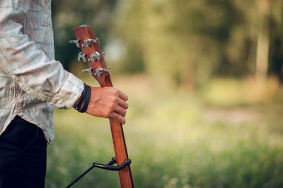 Midsection of man holding guitar in park