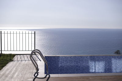 Metal railing by sea against clear sky