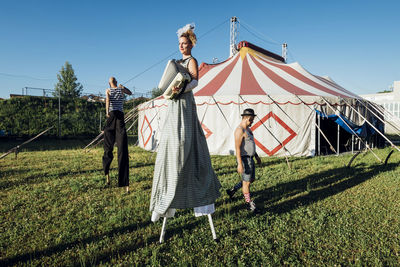 Circus artists performing while walking on meadow