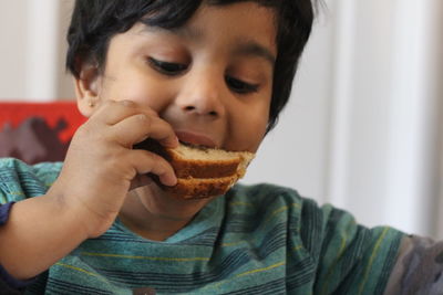Close-up of boy eating bread at home
