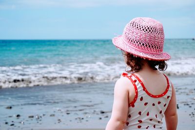 Girl standing on beach against sky