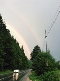 Rainbow over road against sky