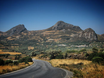 Road amidst mountains against clear blue sky