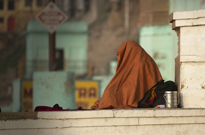 Person covering blanket sitting outside temple